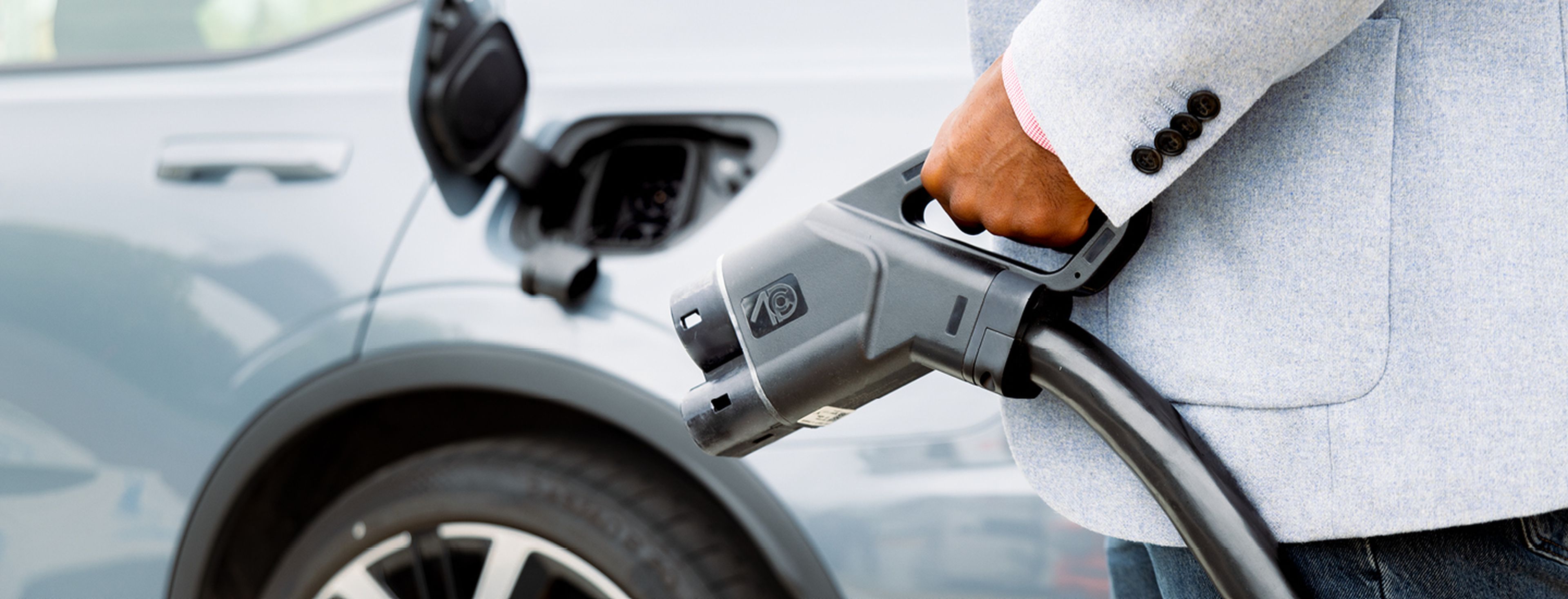 Man in grijs pak houdt elektrische lader vast bij Tango electric