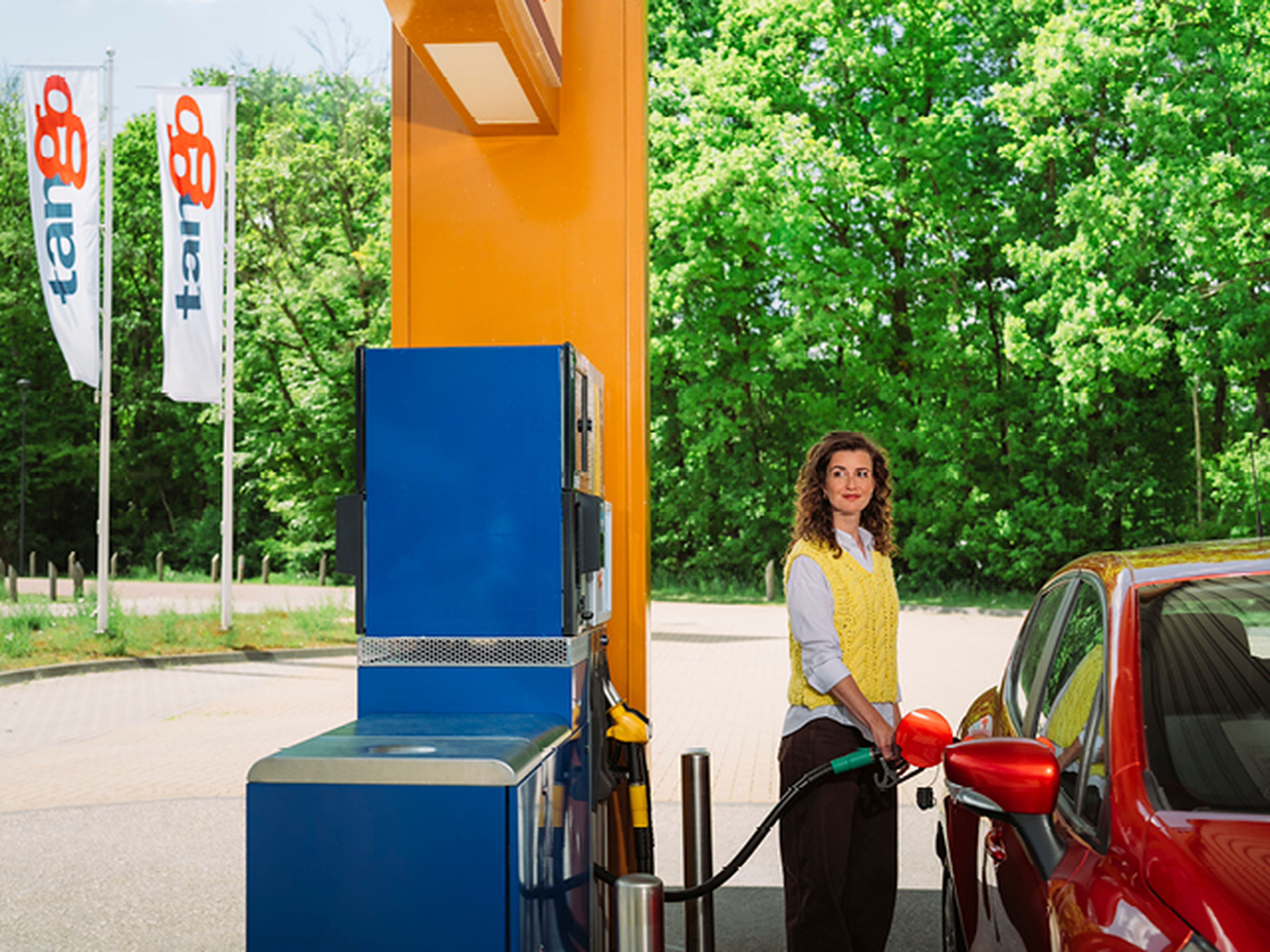 Vrouw tankt rode auto bij een Tango tankstation