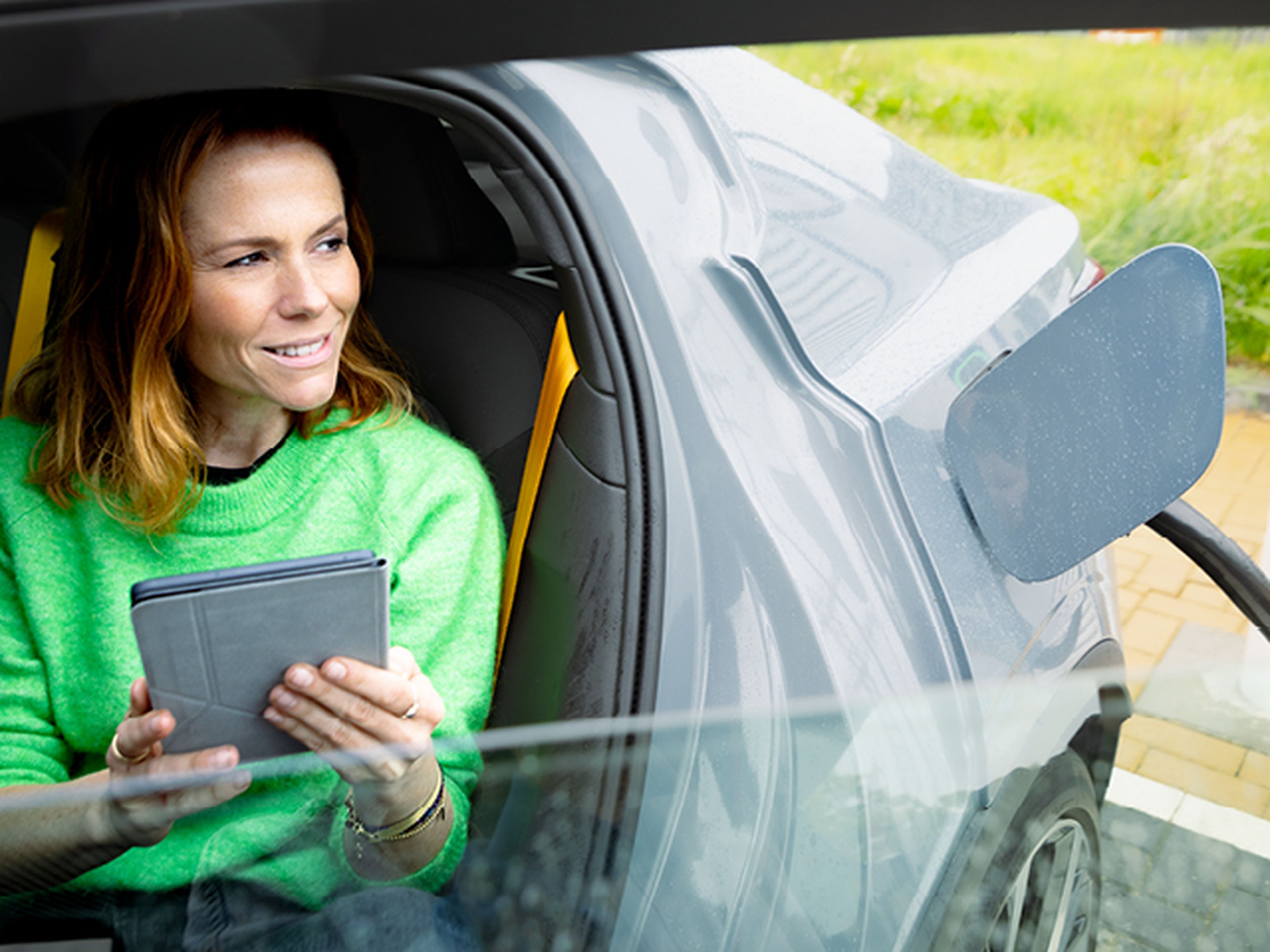 vrouw zit in een auto en kijkt naar een tablet