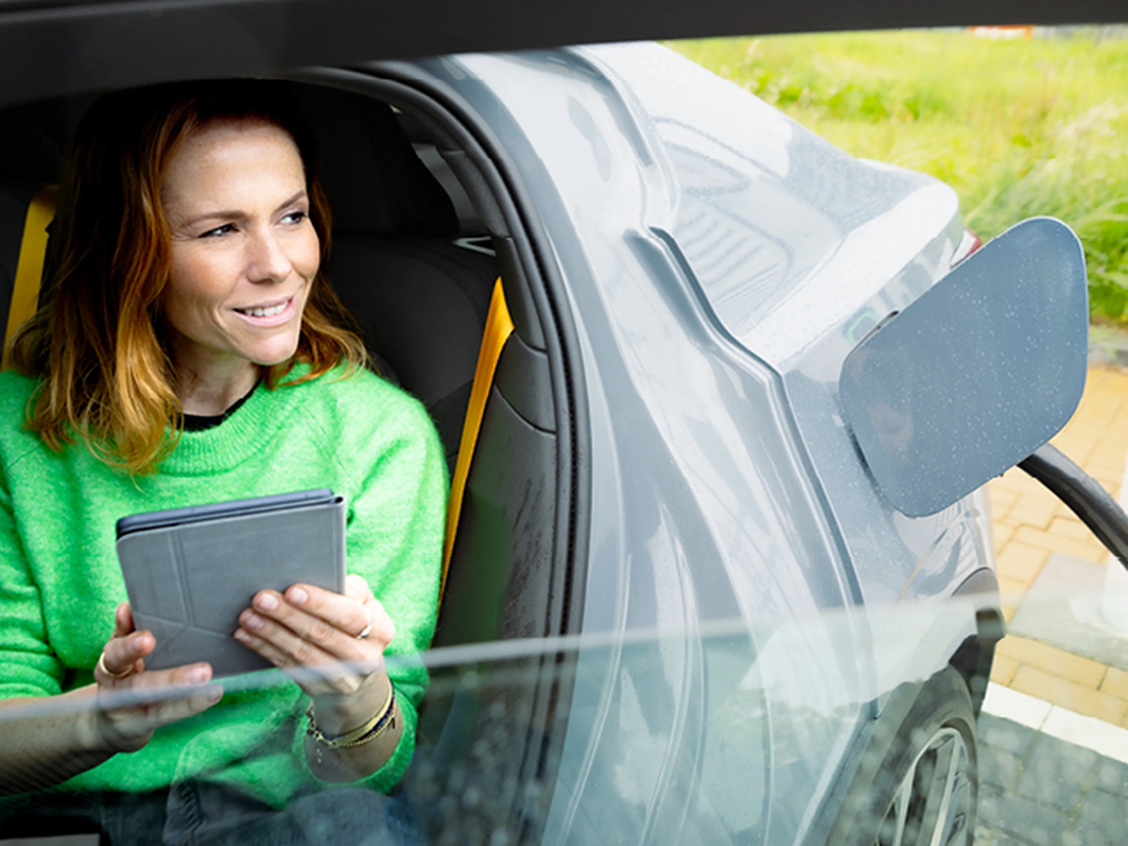vrouw zit in een auto en kijkt naar een tablet