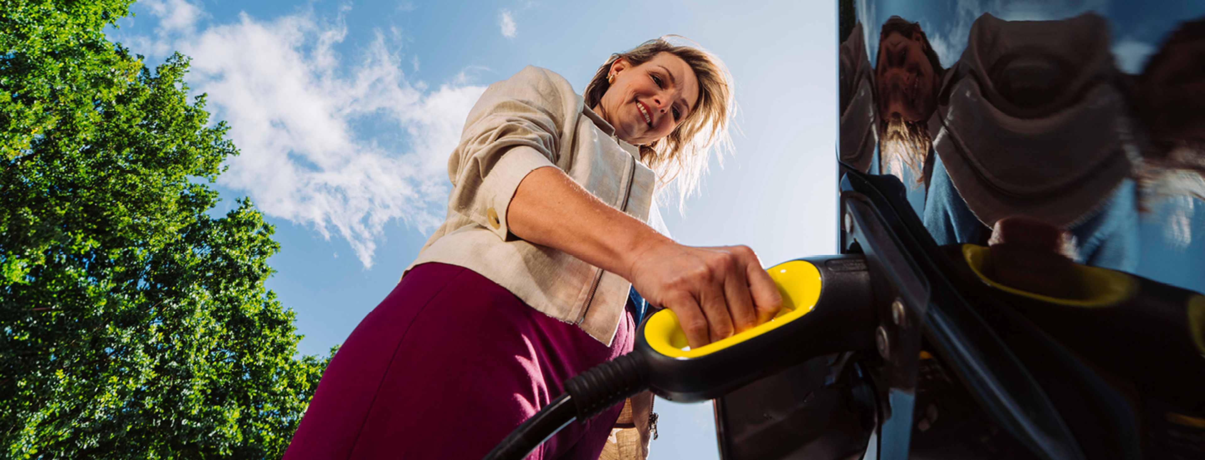 Close-up van een persoon die een gele laadkabel aansluit op een elektrische auto.