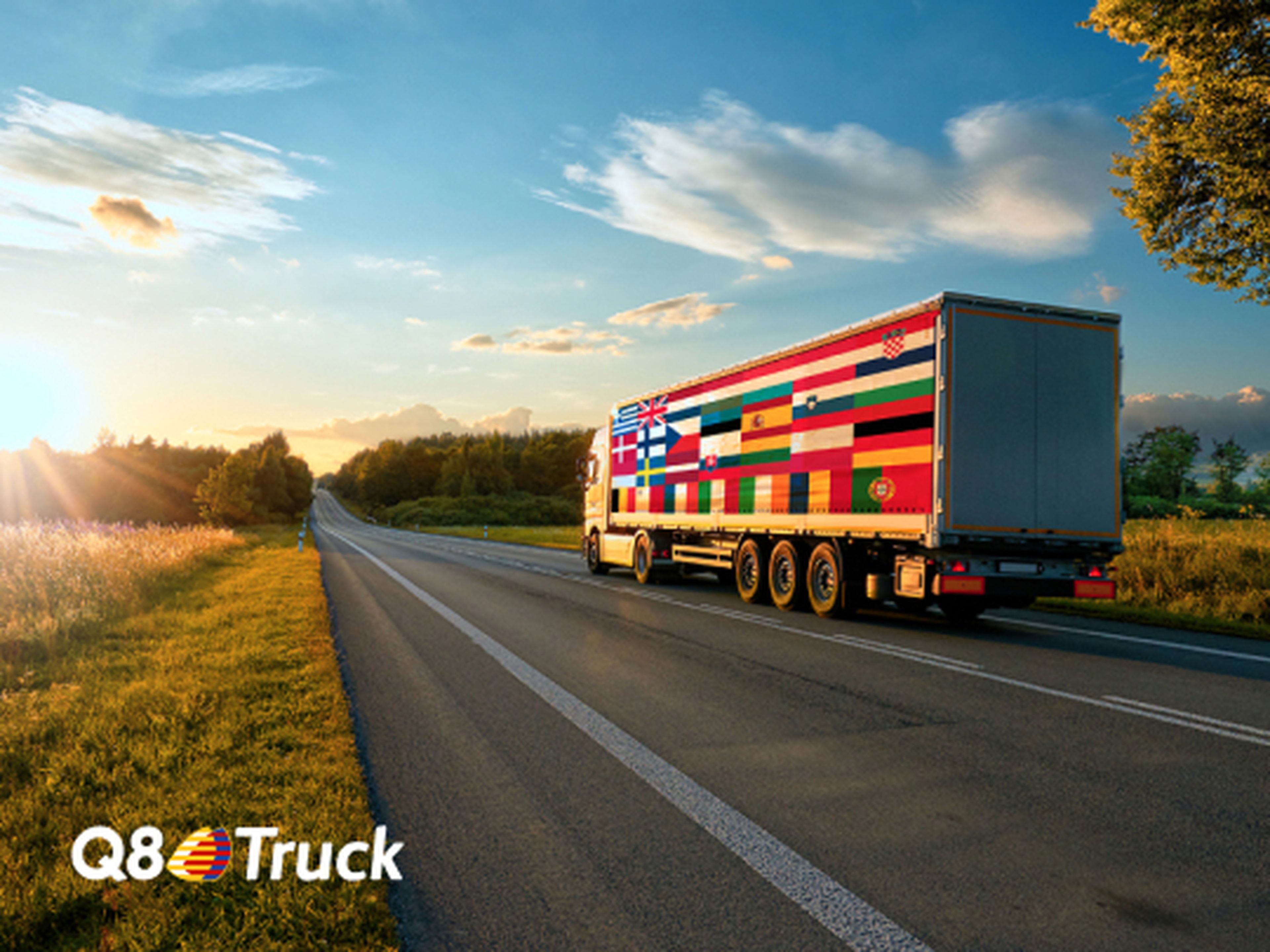 Een vrachtwagen rijdt over een rustige, zonovergoten snelweg in de natuur. Op de zijkant van de oplegger staan vlaggen van verschillende Europese landen, die de internationale dekking van Q8Truck symboliseren.