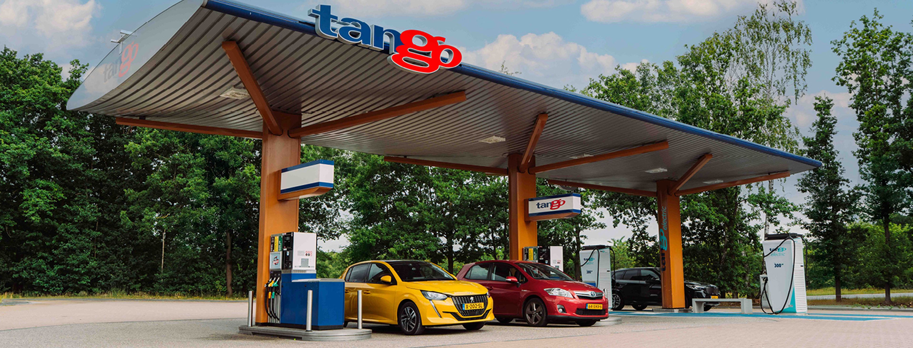 Kinderen drinken terwijl een man een elektrische auto laadt bij een Q8 Electric station