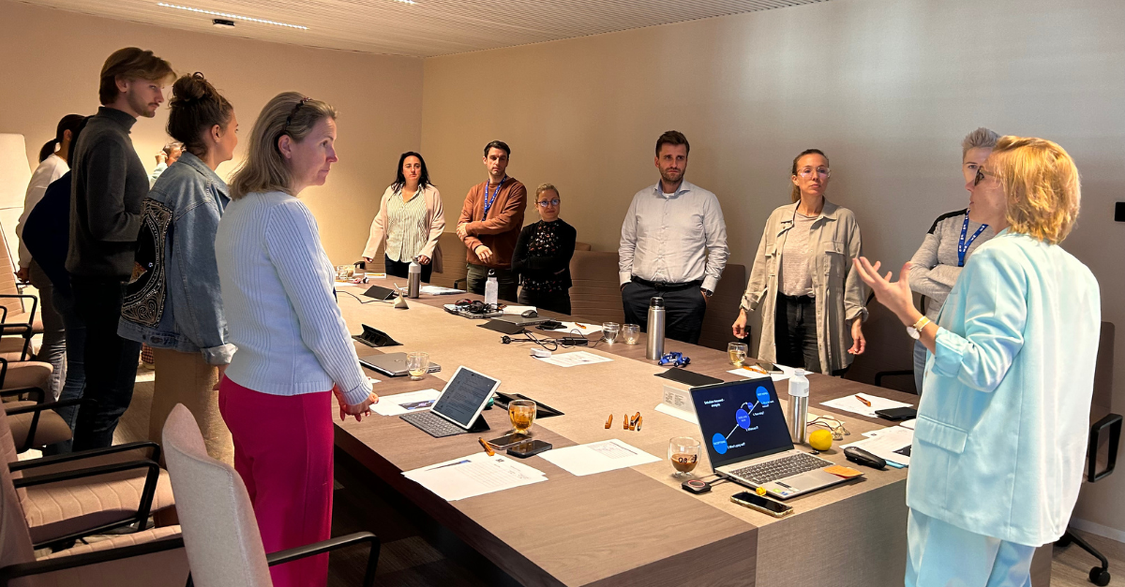 Een grote groep collega's volgt op kantoor een workshop.