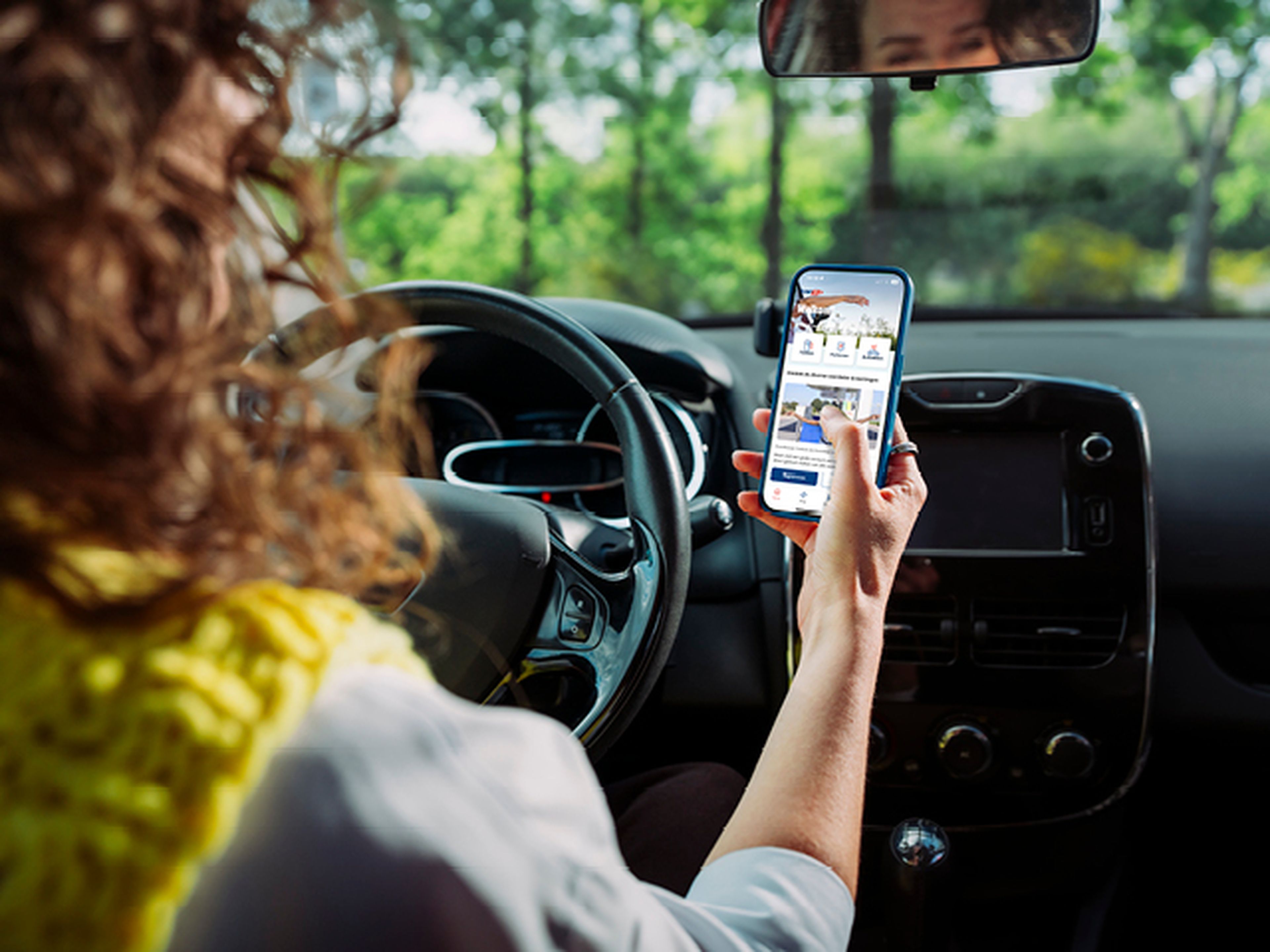 Vrouw staat stil aan Tango tankstation en gebruikt de Tango app op haar smartphone
