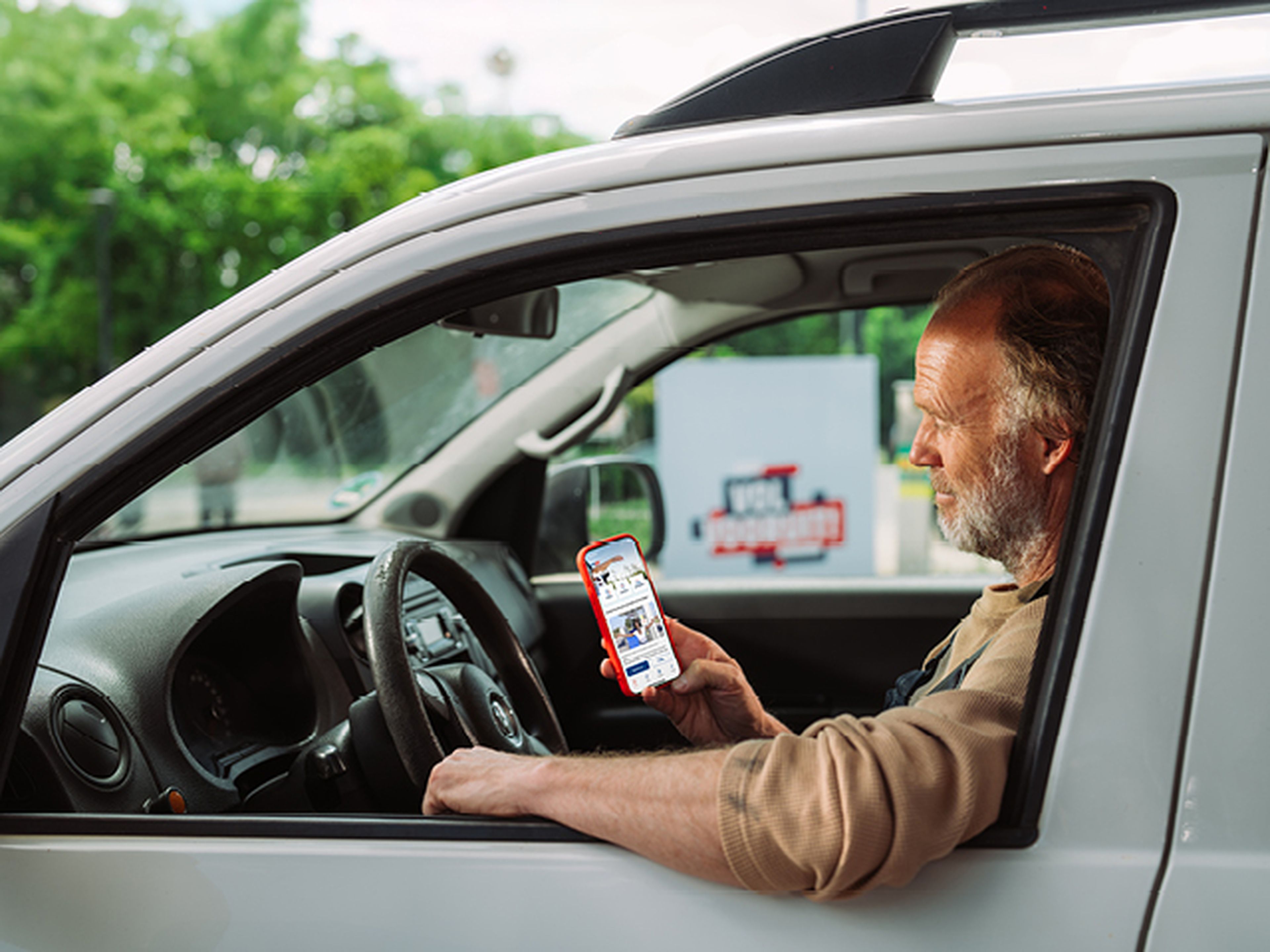 Man zit in zijn auto en kijk naar Tango app op zij smartphone