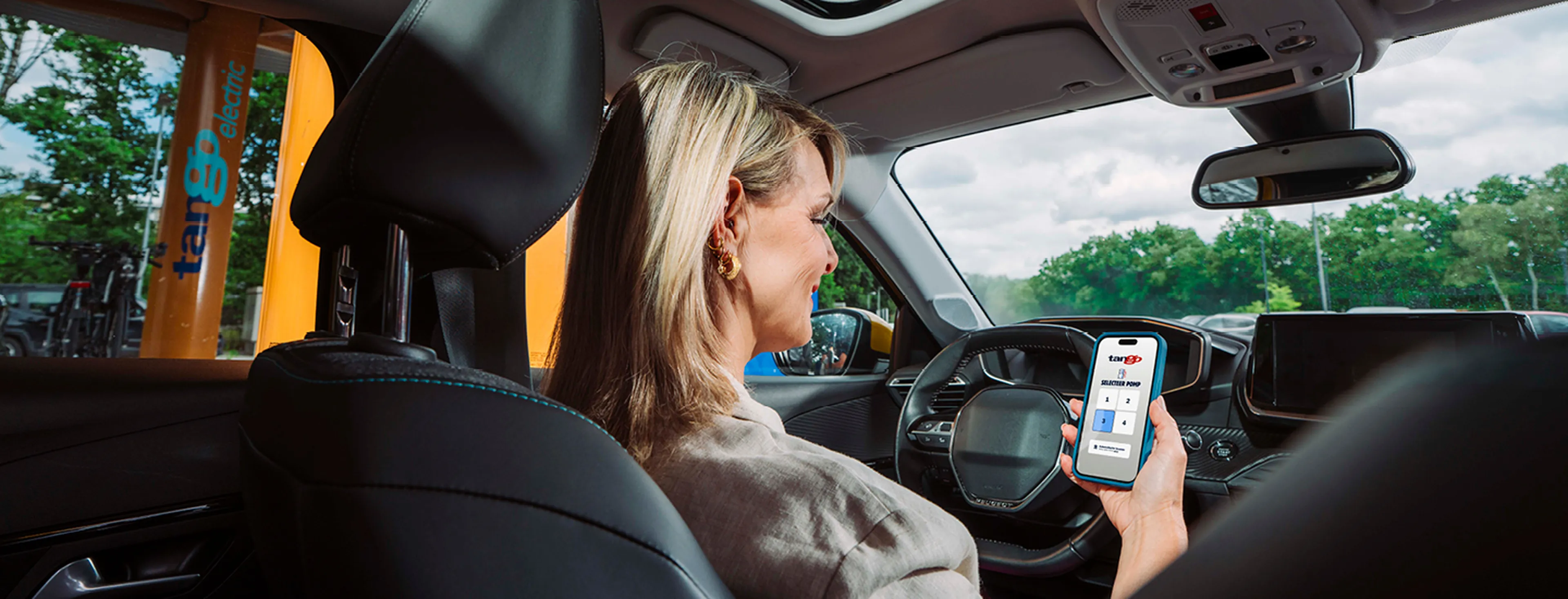 Vrouw bekijkt de Q8 app op haar telefoon bij een Q8 tankstation.