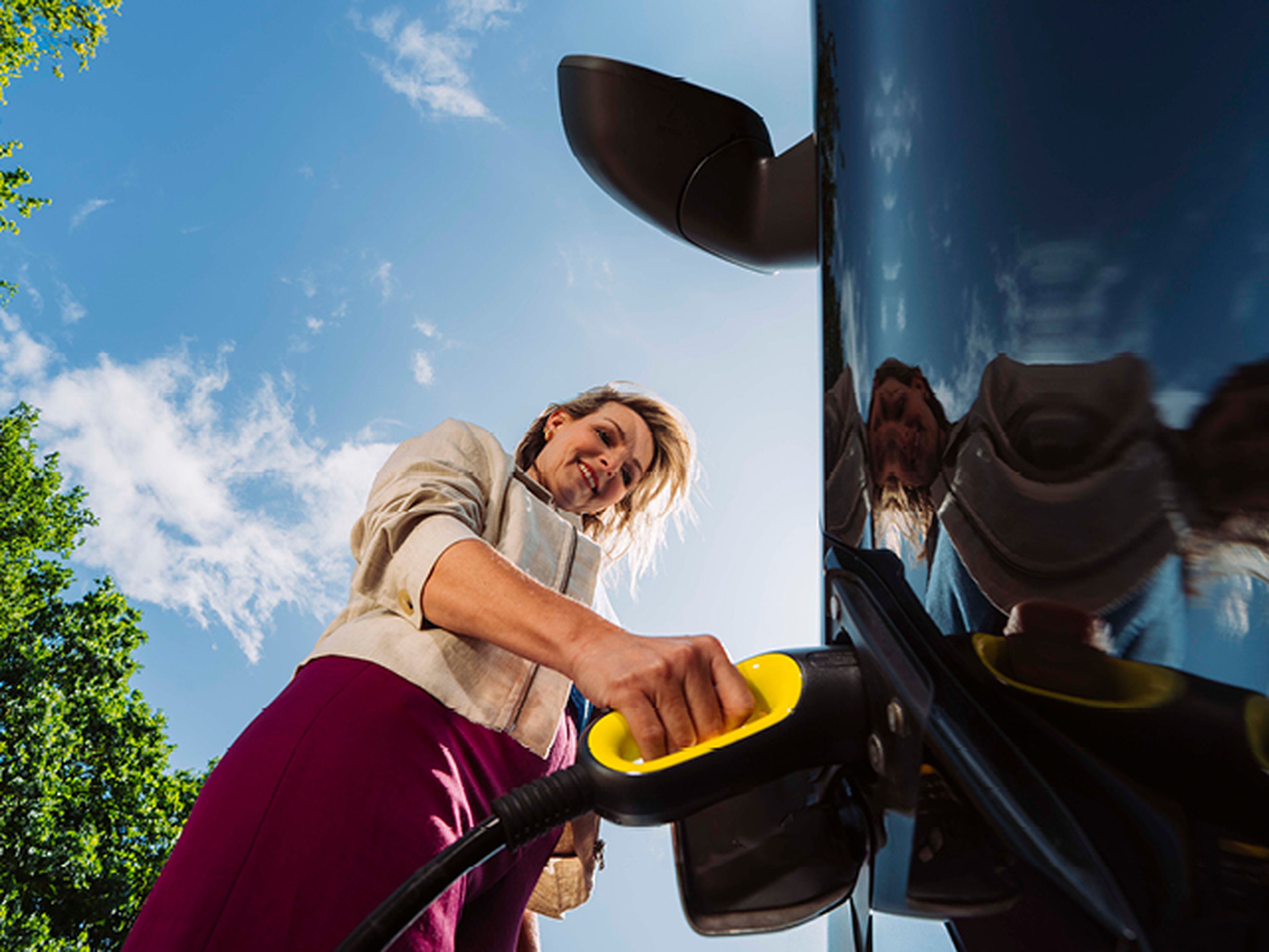 Een zakelijke vrouw die haar auto aan het opladen is bij een Tango electric laadstation