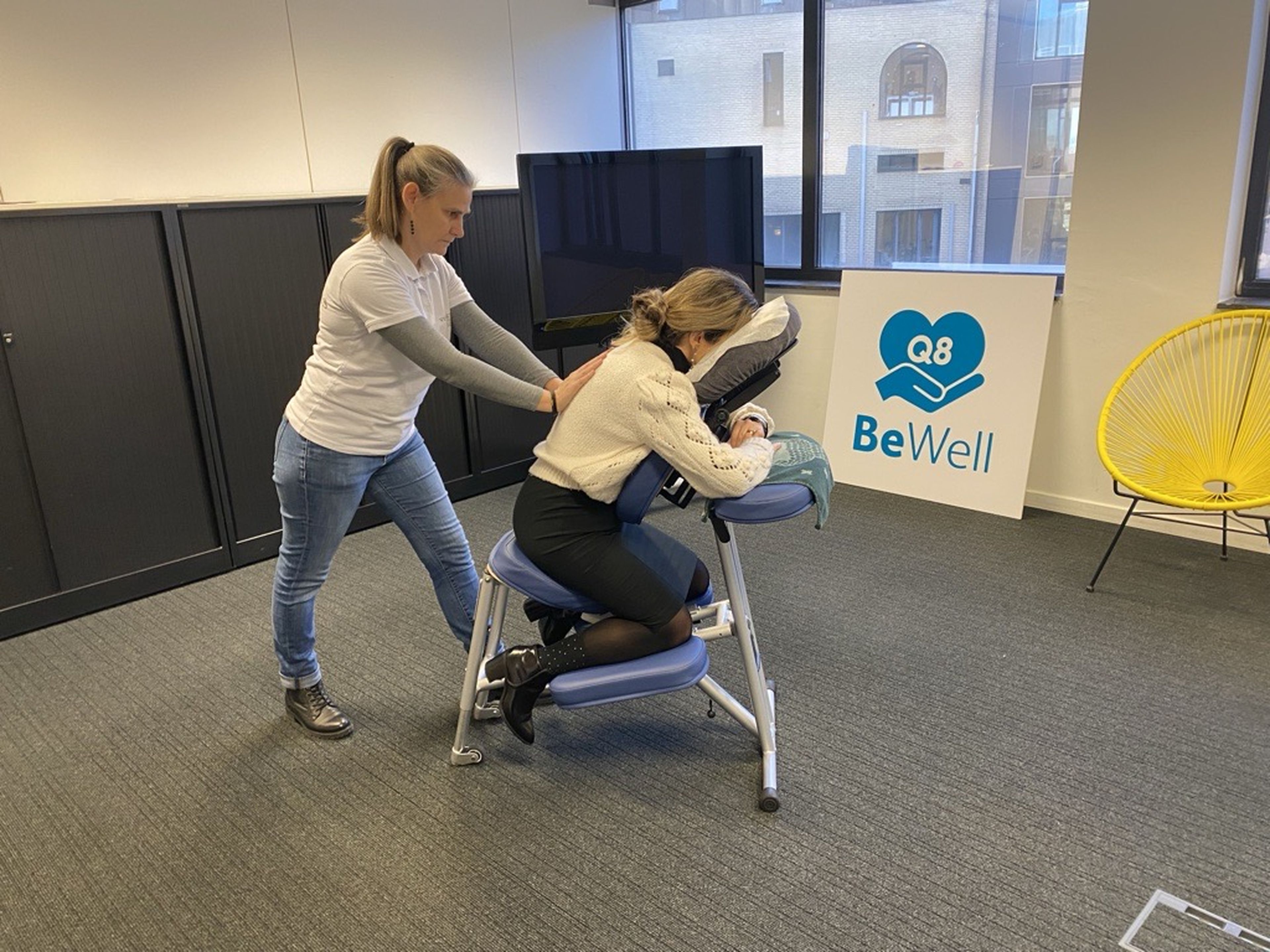 Een vrouw geeft een massage aan een Q8 collega.