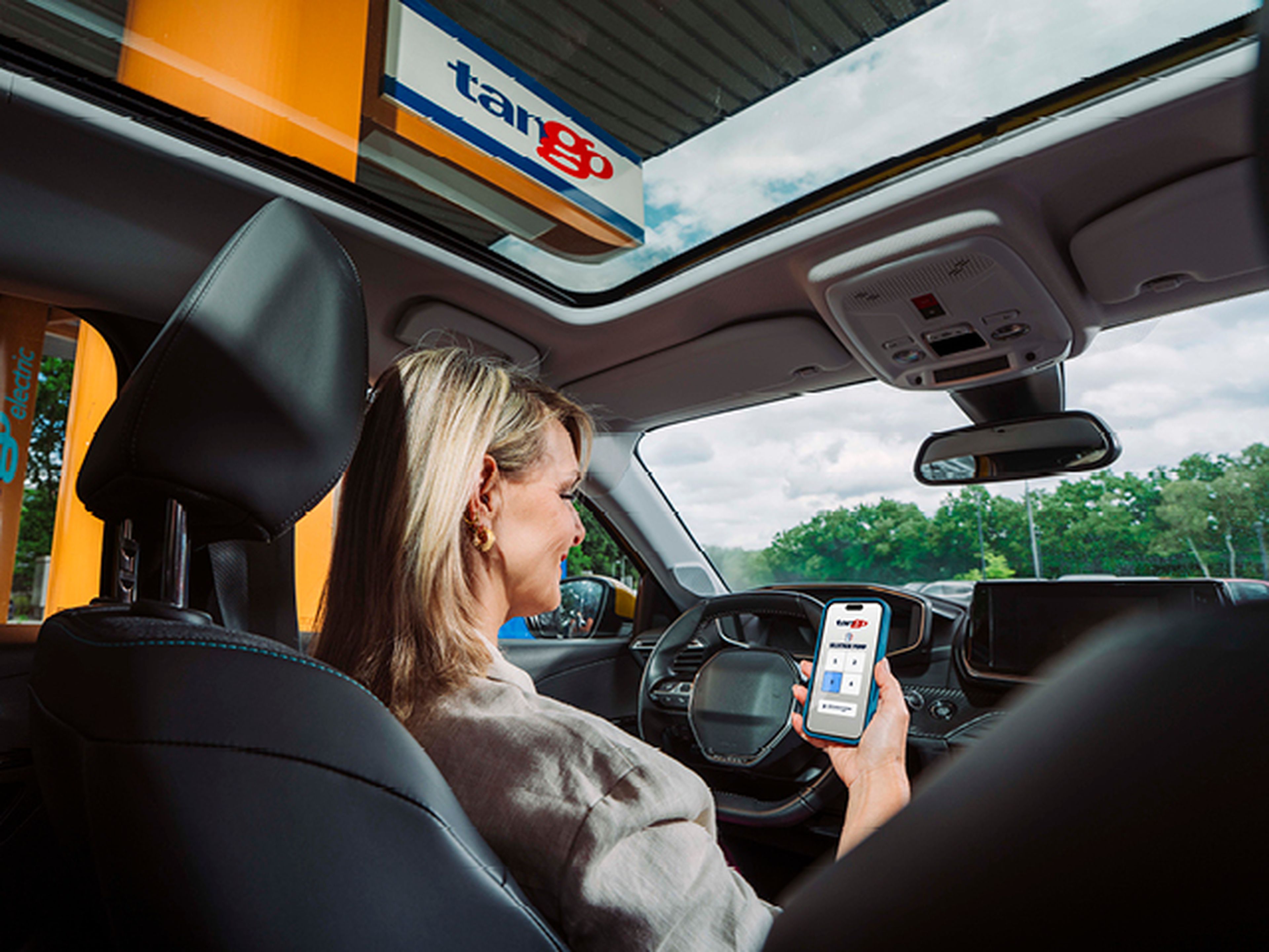Vrouw gebruikt de Tango app in haar auto op het tankstation