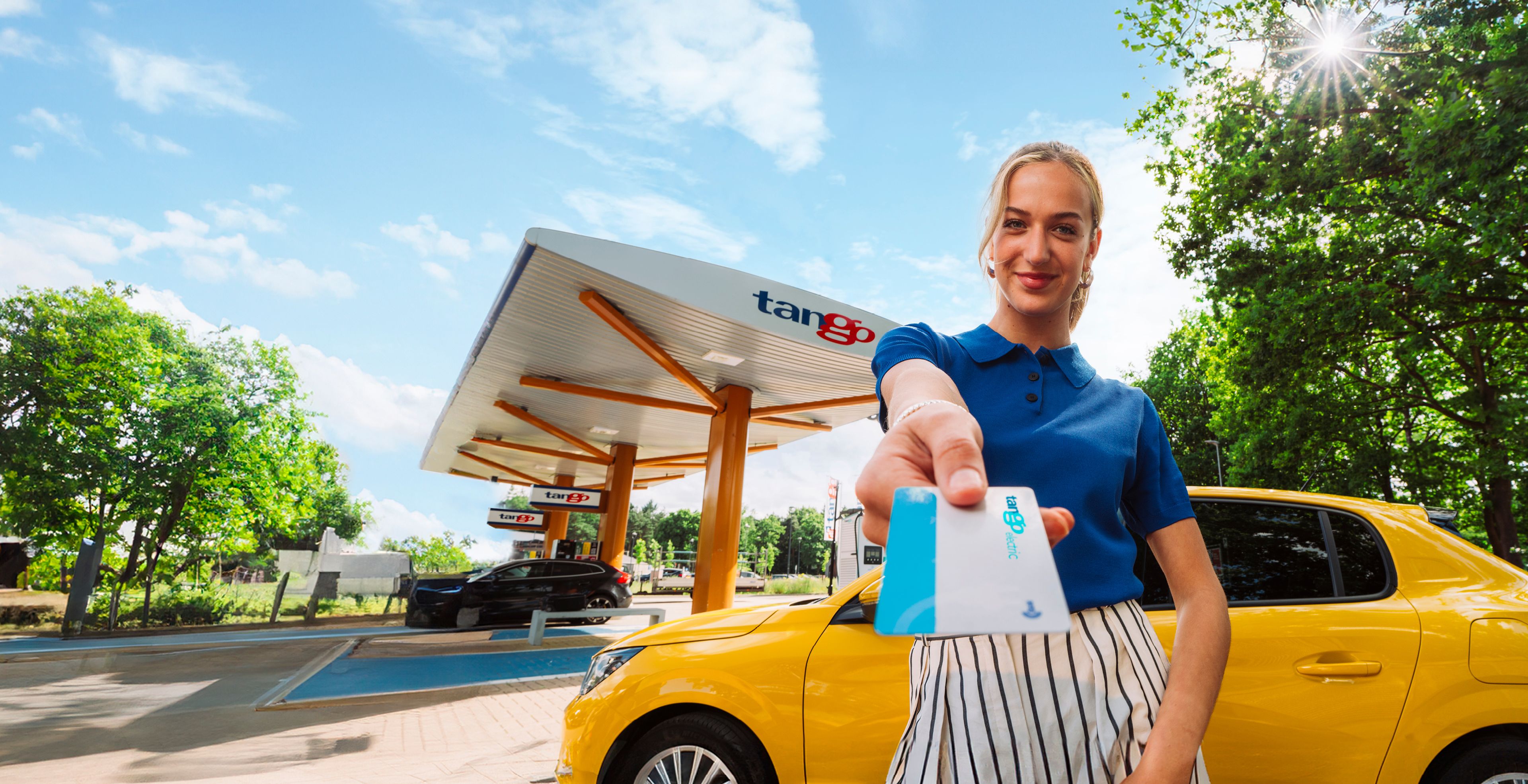 Vrouw bij Tango station voor gele peugeot e-208 toont Tango electric laadpas