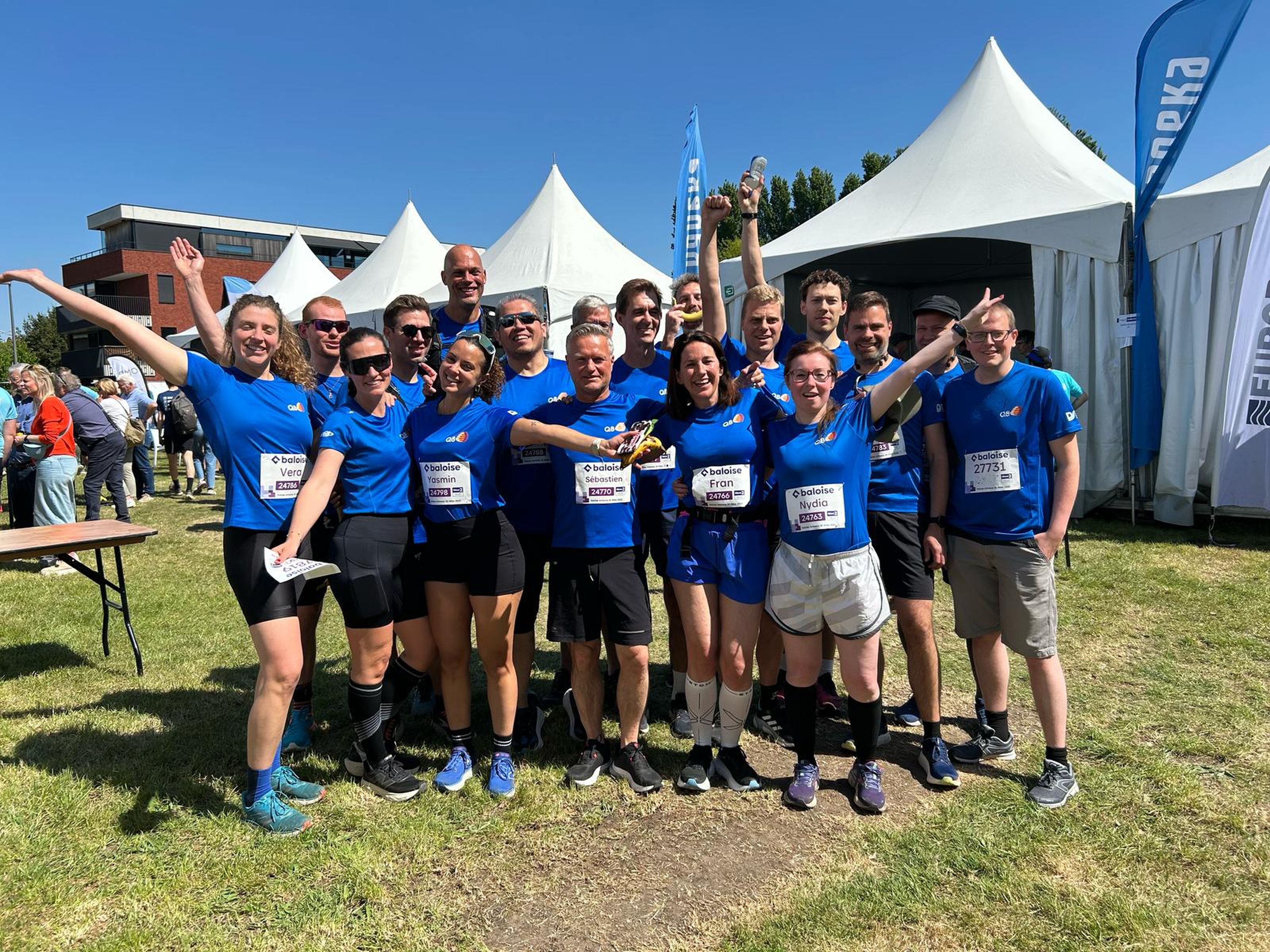 Een groep Q8 collega's neemt een groepsfoto bij de Antwerp 10 Miles.