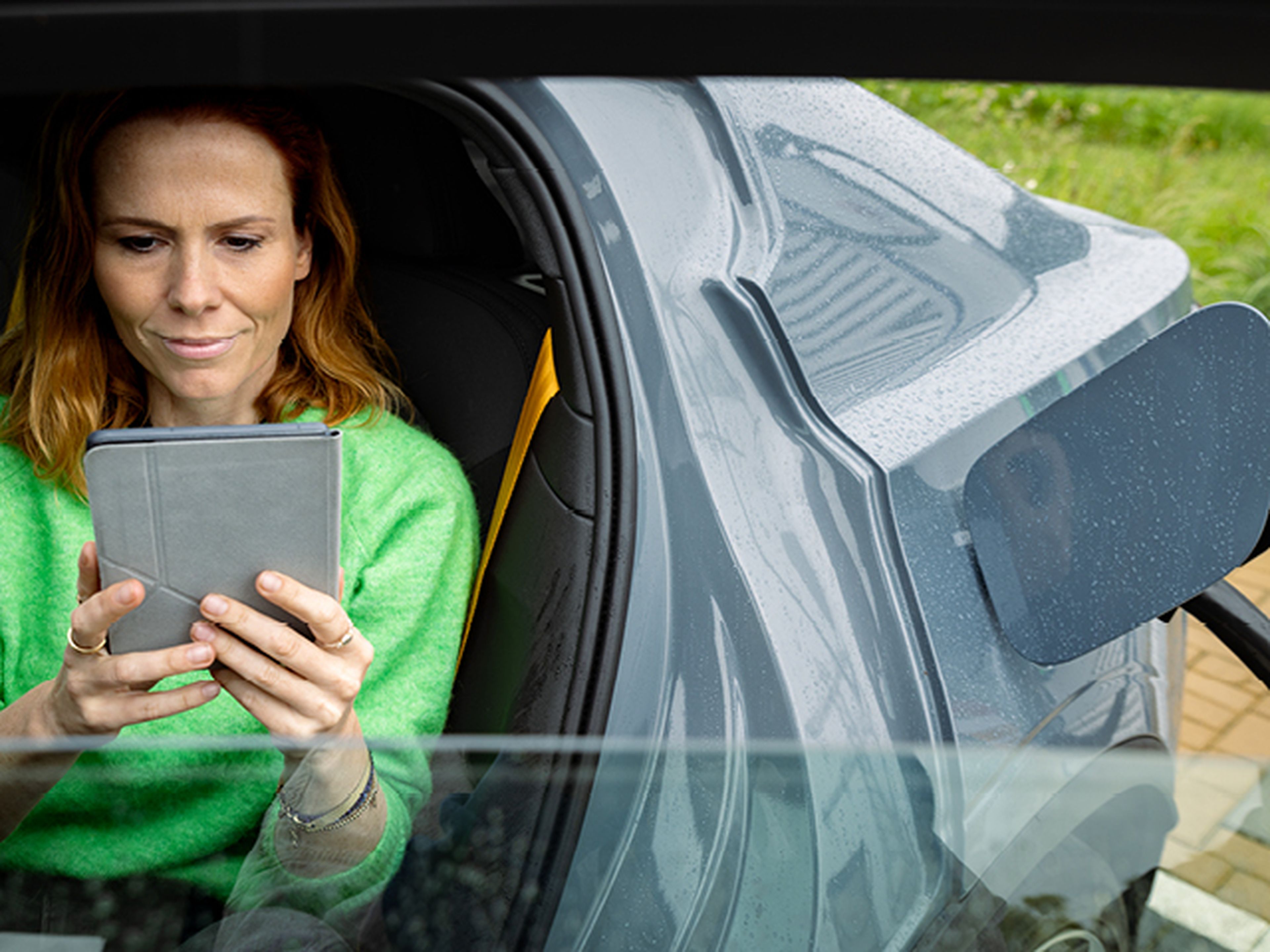 Vrouw zit in haar auto en kijkt naar de Tango liberty web tool op een tablet